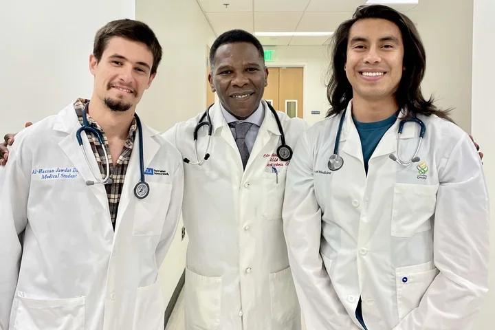 Dr. Ajijola with two lab members in white coats. 