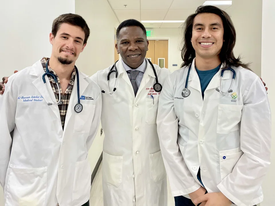 Dr. Ajijola with two lab members in white coats. 