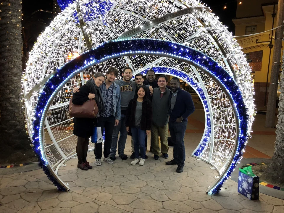 Ajijola Lab members smiling under a blue and white light tunnel at night.