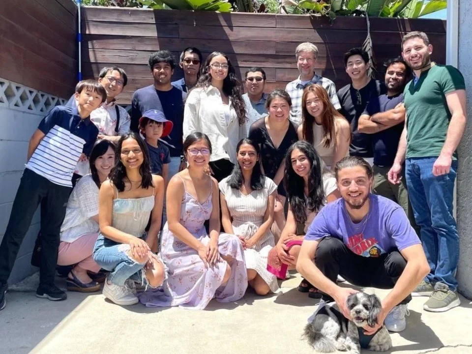 Ajijola Lab members smiling outdoors in sunny weather, with a small dog in the front.